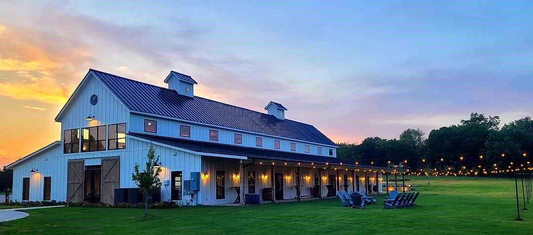 The front of the Primrose Hill barn at sunset with string lights across the lawn